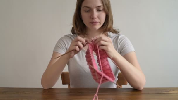 Mujer linda tejiendo un sombrero rosa — Vídeo de stock