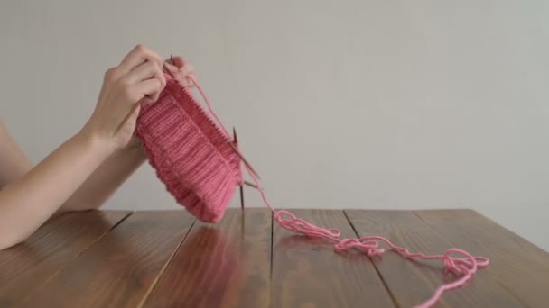 Женские руки вяжущие розовую шляпу — стоковое видео