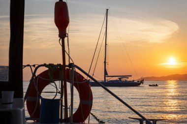 Gün batımında bir adanın önünde güzel bir yelkenli.