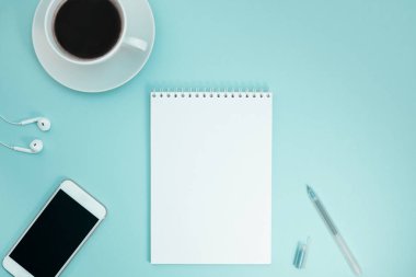 Yaratıcı düz kağıt defter, smartphone, earpieces, kalem ve kopya alan arka plan en az stili ile kahve ile fotoğraf çalışma masası göklere