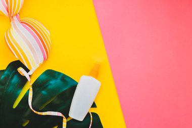 Tropikal orman palm monstera bırakır, güneş gözlüğü, güneş kremi boş şişe mockup ve kadının mayo üst parlak renk kağıt arka plan üzerinde. Metin için yaratıcı düz yatıyordu kavramı şablon yaz tatil