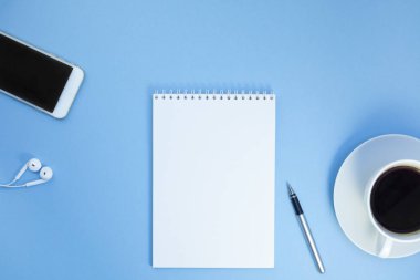 Yaratıcı düz kağıt defter, smartphone, earpieces, kalem ve kopya alan arka plan en az stili ile kahve ile fotoğraf çalışma masası göklere