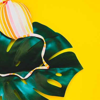 Tropikal orman palmiye monstera yaprakları ve bir kadının mayo üstüne parlak sarı kare Kağıt arka plan. Metin için yaratıcı düz yatıyordu kavramı şablon yaz tatil