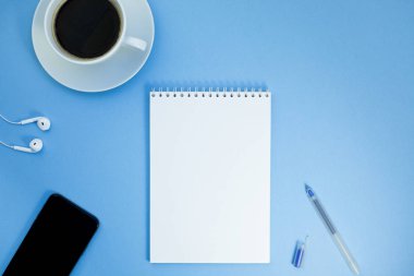Yaratıcı düz kağıt defter, smartphone, earpieces, kalem ve kopya alan arka plan en az stili ile kahve ile fotoğraf çalışma masası göklere