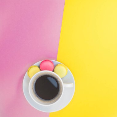 Kopya alanı en az pembe ve sarı arka plan stili ile fotoğraf kahve fincanı ve macaroons ve yaratıcı kare düz göklere