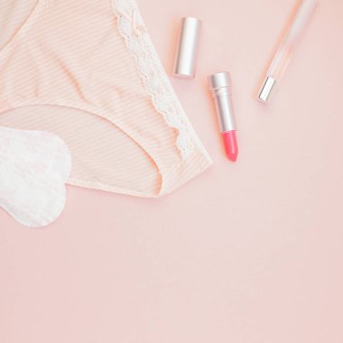 Kare kadınsı düz metin için kopya yer moda blog ve sosyal medya için pastel pembe renk zemin üzerine kadın iç çamaşırı ve aksesuarları, parfüm, ruj ve yastıkları gömlekleri set koymak