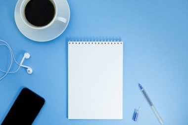 Yaratıcı düz kağıt defter, smartphone, earpieces, kalem ve kopya alan arka plan en az stili ile kahve ile fotoğraf çalışma masası göklere