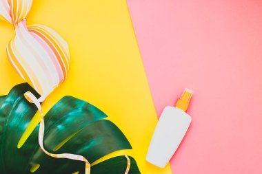 Tropikal orman palm monstera bırakır, güneş gözlüğü, güneş kremi boş şişe mockup ve kadının mayo üst parlak renk kağıt arka plan üzerinde. Metin için yaratıcı düz yatıyordu kavramı şablon yaz tatil