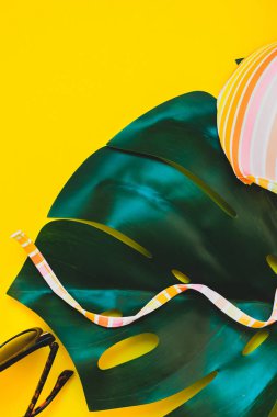 Tropikal orman palm monstera, güneş gözlüğü ve parlak sarı kağıt arka plan bir kadının mayo üstüne bırakır. Metin için yaratıcı düz yatıyordu kavramı şablon yaz tatil