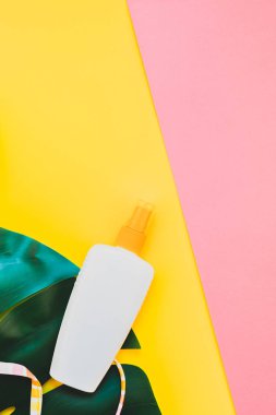 Tropikal orman palm monstera bırakır, güneş gözlüğü, güneş kremi boş şişe mockup ve kadının mayo üst parlak renk kağıt arka plan üzerinde. Metin için yaratıcı düz yatıyordu kavramı şablon yaz tatil