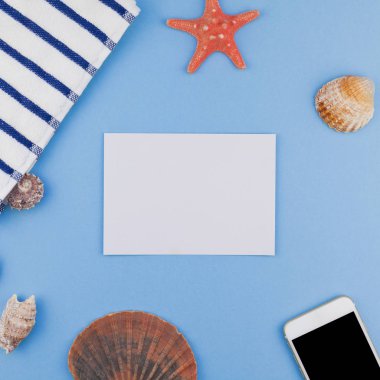 Yaratıcı kare düz yaz seyahat tatil kavramı yatıyordu. Plaj havlusu, deniz kabuklarını, deniz yıldızı ve pastel mavi arka plan kopya alanı en az tarzı, metin için şablon ile smartphone Üstten Görünüm