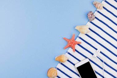 Yaratıcı düz yaz seyahat tatil kavramı yatıyordu. Plaj havlusu, deniz kabuklarını, deniz yıldızı ve pastel mavi arka plan kopya alanı en az tarzı, metin için şablon ile smartphone Üstten Görünüm