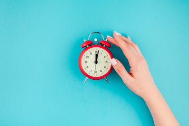 Yaratıcı düz yatıyordu kavramı kırmızı vintage çalar saat parlak mavi turkuaz üzerinde tutan kadın el üst görünümünü renk Kağıt arka plan kopya alanı ile en az tarzı, metin için şablon