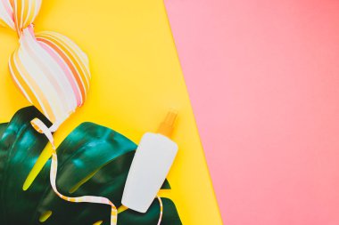 Tropikal orman palm monstera bırakır, güneş gözlüğü, güneş kremi boş şişe mockup ve kadının mayo üst parlak renk kağıt arka plan üzerinde. Metin için yaratıcı düz yatıyordu kavramı şablon yaz tatil