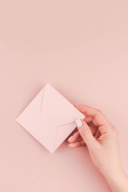 Kadın el kopya alanı bin yıllık pembe bir arka plan üzerinde küçük aşk mektubu minimalizm tarzı tutarak yaratıcı görüntü. Kavram şablon kadınsı blog, sosyal medya için