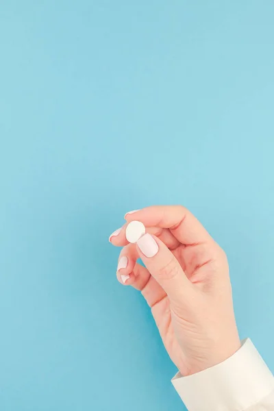 Vrouw Hand Met Een Witte Pil Pastel Blauw Papier Achtergrond — Stockfoto