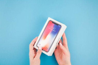 Berlin, Almanya - 24 Mayıs 2018: parlak mavi arka planı renkli kutuyu son Apple iphone X 10 akıllı telefon holding kadın eller. Unboxing kavramı kopya alanı ile