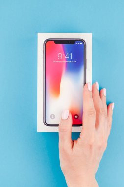 Berlin, Almanya - 24 Mayıs 2018: parlak mavi arka planı renkli kutuyu son Apple iphone X 10 akıllı telefon holding kadın eller. Unboxing kavramı kopya alanı ile