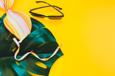 Tropikal orman palm monstera, güneş gözlüğü ve parlak sarı kağıt arka plan bir kadının mayo üstüne bırakır. Metin için yaratıcı düz yatıyordu kavramı şablon yaz tatil
