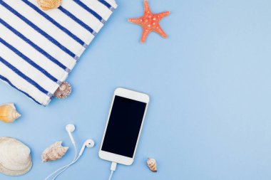 Yaratıcı düz yaz seyahat tatil kavramı yatıyordu. Plaj havlusu, deniz kabuklarını, deniz yıldızı ve pastel mavi arka plan kopya alanı en az tarzı, metin için şablon ile smartphone Üstten Görünüm