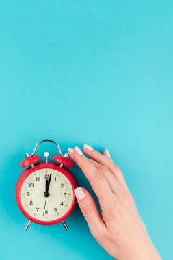 Yaratıcı düz yatıyordu kavramı kırmızı vintage çalar saat parlak mavi turkuaz üzerinde tutan kadın el üst görünümünü renk Kağıt arka plan kopya alanı ile en az tarzı, metin için şablon