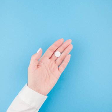 En az tarzı, kare şablon metin için kopya alanı pastel kağıt mavi zemin üzerine beyaz bir hap tutan kadın el. Tıbbi tedavi, eczane, sağlık kavramı