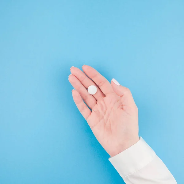 Mano Mujer Sosteniendo Una Píldora Blanca Sobre Fondo Papel Azul —  Fotos de Stock