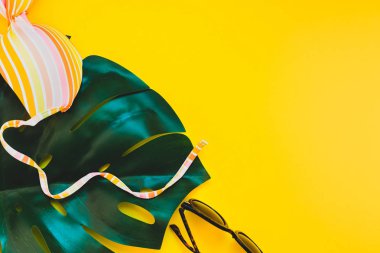 Tropikal orman palm monstera, güneş gözlüğü ve parlak sarı kağıt arka plan bir kadının mayo üstüne bırakır. Metin için yaratıcı düz yatıyordu kavramı şablon yaz tatil
