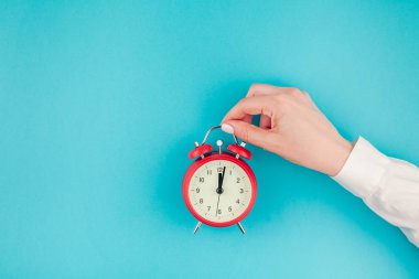 Yaratıcı düz yatıyordu kavramı üstten görünüm kadının el Beyaz gömlek kırmızı vintage çalar saat parlak mavi turkuaz renkli kağıt arka plan kopya alanı ile üzerinde en az stil, şablon metin için holding