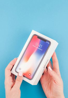 Berlin, Almanya - 24 Mayıs 2018: parlak mavi arka planı renkli kutuyu son Apple iphone X 10 akıllı telefon holding kadın eller. Unboxing kavramı kopya alanı ile