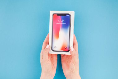 Berlin, Almanya - 24 Mayıs 2018: parlak mavi arka planı renkli kutuyu son Apple iphone X 10 akıllı telefon holding kadın eller. Unboxing kavramı kopya alanı ile