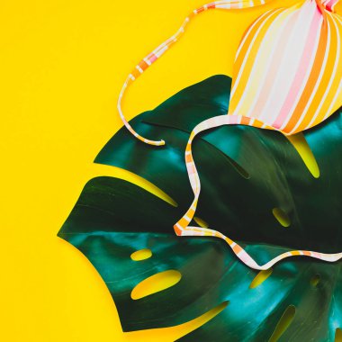 Tropikal orman palmiye monstera yaprakları ve bir kadının mayo üstüne parlak sarı kare Kağıt arka plan. Metin için yaratıcı düz yatıyordu kavramı şablon yaz tatil