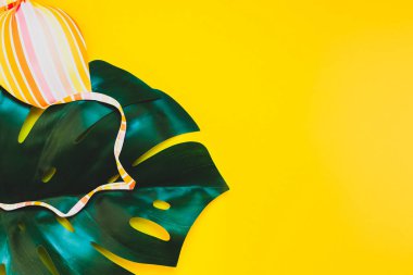Tropikal orman palmiye monstera yaprakları ve bir kadının mayo üstüne parlak sarı kağıt arka plan. Metin için yaratıcı düz yatıyordu kavramı şablon yaz tatil