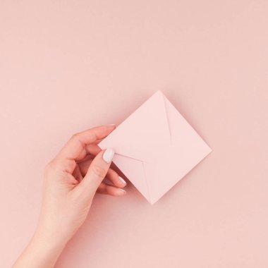 Kadın el kopya alanı bin yıllık pembe bir arka plan üzerinde küçük aşk mektubu minimalizm tarzı tutarak yaratıcı görüntü. Kare kavramı şablon kadınsı blog, sosyal medya için
