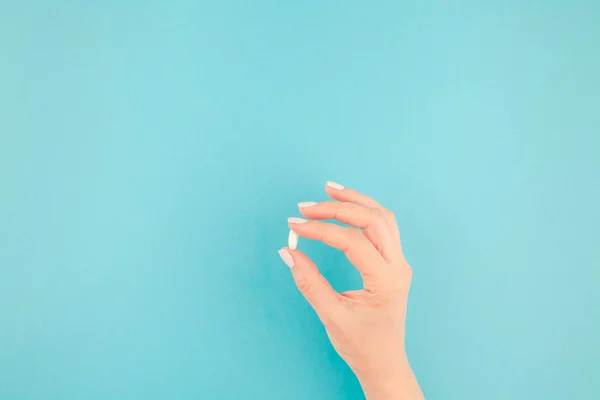 Mano Mujer Sosteniendo Una Píldora Blanca Sobre Fondo Papel Azul — Foto de Stock