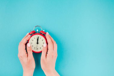 Yaratıcı düz yatıyordu kavramı üstten görünüm kadının en az stil, şablon metin için kopya alanı ile parlak mavi turkuaz renkli kağıt arka plan üzerinde kırmızı vintage çalar saat tutan eller