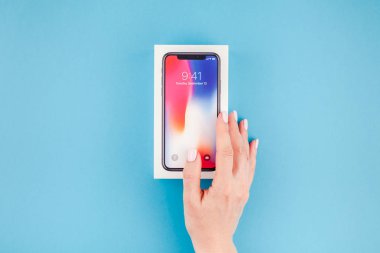 Berlin, Almanya - 24 Mayıs 2018: parlak mavi arka planı renkli kutuyu son Apple iphone X 10 akıllı telefon holding kadın eller. Unboxing kavramı kopya alanı ile