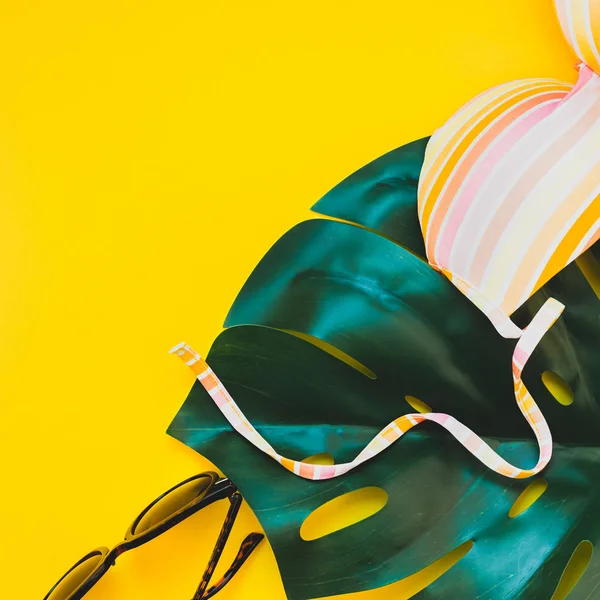 Tropikal orman palm monstera bırakır, güneş gözlüğü ve bir kadının mayo üstüne parlak kare Kağıt arka plan sarı. Metin için yaratıcı düz yatıyordu kavramı şablon yaz tatil