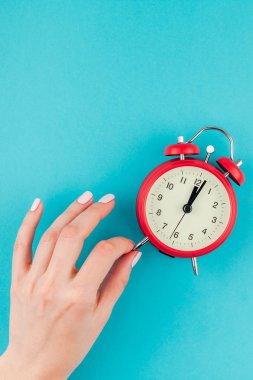 Yaratıcı düz yatıyordu kavramı kırmızı vintage çalar saat parlak mavi turkuaz üzerinde tutan kadın el üst görünümünü renk Kağıt arka plan kopya alanı ile en az tarzı, metin için şablon
