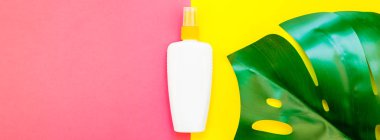 Tropikal orman palmiye monstera yaprakları ve güneş koruyucu boş şişe mockup parlak sarı ve pembe çift ton kağıt arka plan üzerinde. Yaz yaratıcı düz yatıyordu kavramı Şablon metnini tatiller. Uzun geniş afiş