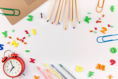 Çalar saat, renk okulu ve ofis malzemelerini kopya alanı, çerçeve, metin veya tasarım şablonu olan beyaz masa arkaplanına yerleştirerek okul kavramına yaslan
