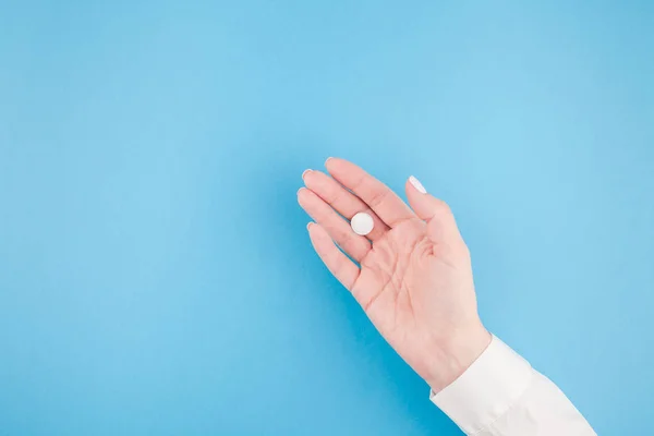 ミニマル スタイル テキストのテンプレート コピー スペースとパステル調の青紙の背景に白い錠剤を持つ女性の手 医療の概念 — ストック写真