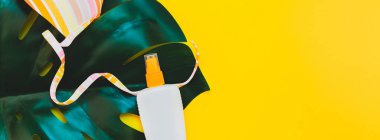 Tropikal orman palm monstera, güneş koruyucu boş şişe mockup ve kadının mayo parlak sarı Kağıt arka plan üzerinde bırakır. Yaz yaratıcı düz yatıyordu kavramı Şablon metnini tatiller. Uzun geniş afiş