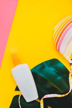 Tropikal orman palm monstera bırakır, güneş gözlüğü, güneş kremi boş şişe mockup ve kadının mayo üst parlak renk kağıt arka plan üzerinde. Metin için yaratıcı düz yatıyordu kavramı şablon yaz tatil