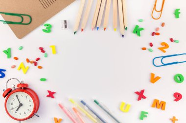 Çalar saat, renk okulu ve ofis malzemelerini kopya alanı, çerçeve, metin veya tasarım şablonu olan beyaz masa arkaplanına yerleştirerek okul kavramına yaslan