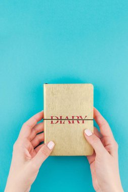 Küçük altın defter günlüğü turkuaz Kağıt arka plan üzerinde kopya alanı ile minimalizm tarzı holding kadın eller yaratıcı düz yatıyordu. Kadınsı blog, sosyal medya için şablon