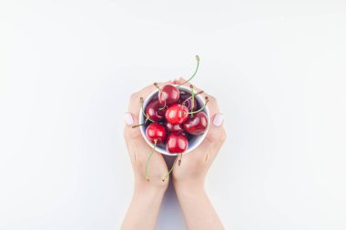 Yaratıcı üstten görünüm taze olgun kiraz bir kase elleriniz ve beyaz arka plan üzerinde en az stili izole kopya alanı. Yaz eğlenceli ve sağlıklı beslenme kavramı. Metin veya gıda tasarımınız için şablon