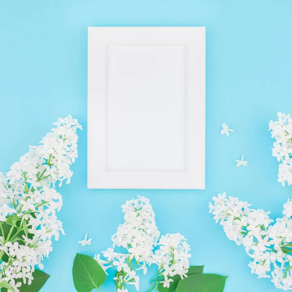 Boş Kartpostal çerçeve sahte kavramı en iyi görünümünü kare düz yığmak ve yaprakları kopya alanı en az stili, yazı, metin veya tasarım şablonu pastel mavi zemin üzerine beyaz leylak çiçekler