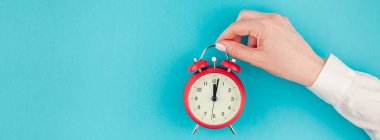 Yaratıcı düz yatıyordu kavramı üstten görünüm kadının el Beyaz gömlekli minimal tarzda uzun geniş afiş kopya alanı ile parlak mavi turkuaz renkli kağıt arka plan üzerinde kırmızı vintage çalar saat tutan