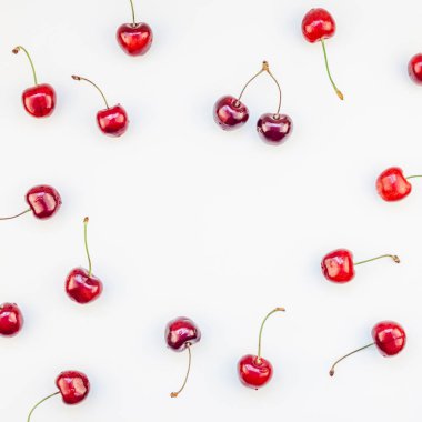 Üstten görünüm taze olgun kiraz desen düzeninin en az tarzında beyaz arka plan üzerinde izole kopya alanı ile kare. Yaz eğlenceli ve sağlıklı beslenme kavramı. Metin veya gıda tasarımınız için şablon